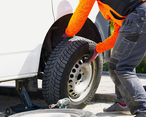 Mobile tyre technician fitting a tyre at roadside